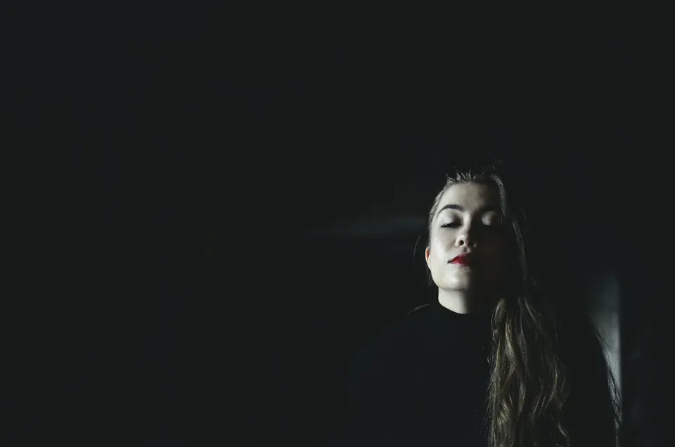 Woman in the dark, only her face grazed by light