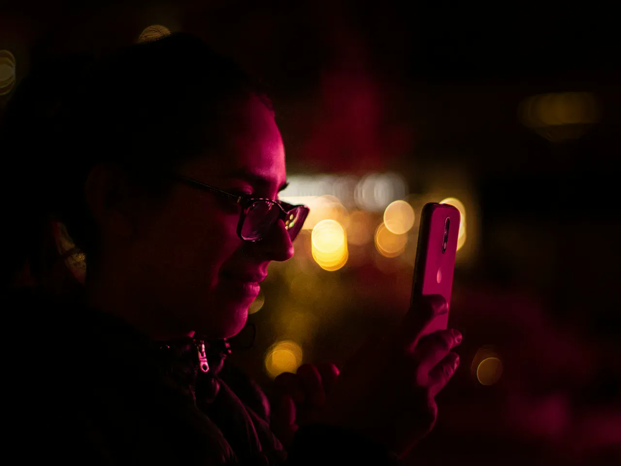 Frau blickt abends auf ihr leuchtendes Telefon