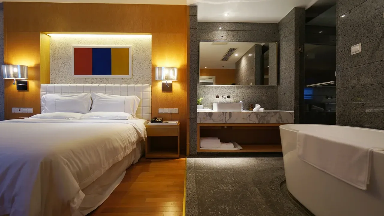 An elegant hotel room with a wide bed in subdued evening light