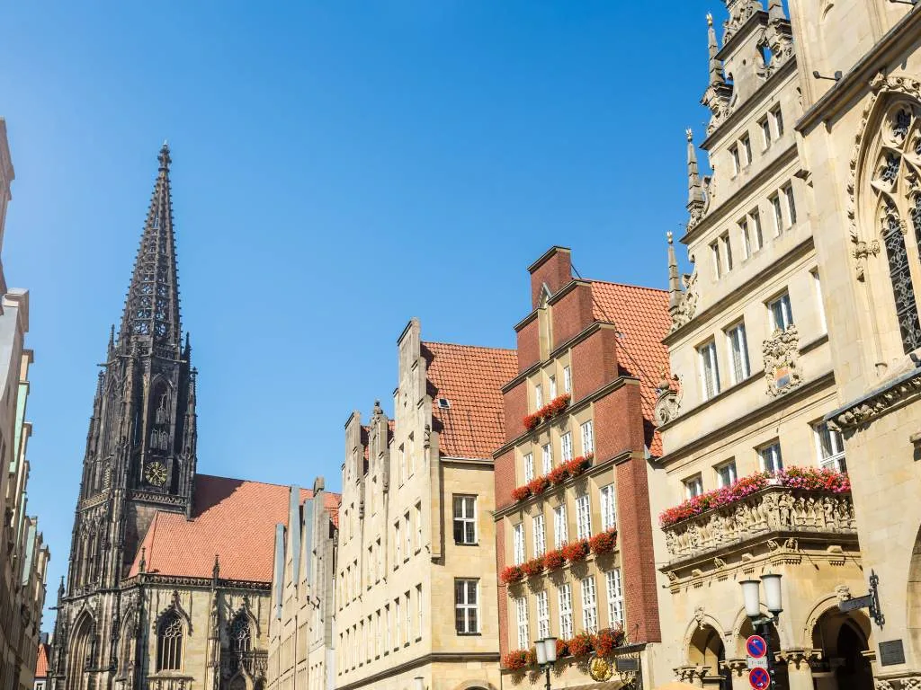 Giebelhäuser am Prinzipalmarkt vor blauem Himmel, dahinter der Turm der Lambertikirche