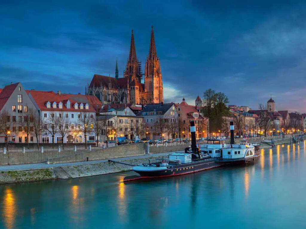 Der Donaukai zur blauen Stunde, ein Schiff am Ufer und die Türme des Doms dahinter