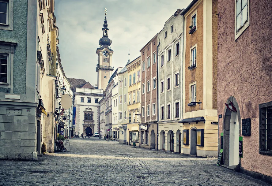 A cobbled lane in the Linz old town with the tower of the Old Town Hall at the end