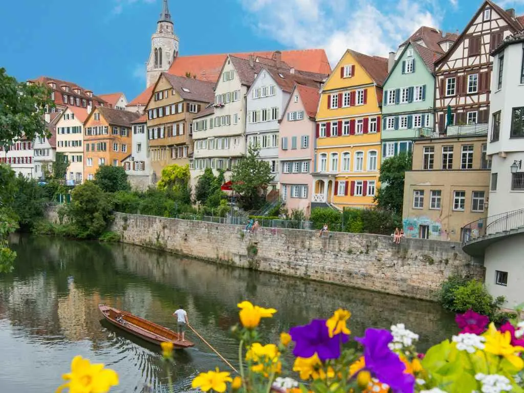 Die bunten Häuser der Tübinger Neckarfront über dem Wasser, davor ein Stocherkahn