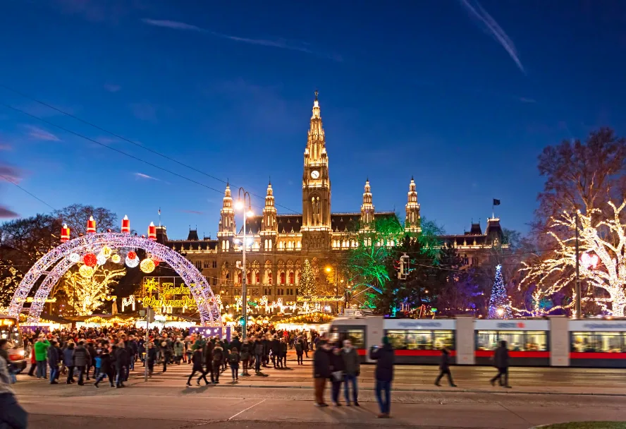 Der Christkindlmarkt vor dem beleuchteten Wiener Rathaus, davor eine Straßenbahn