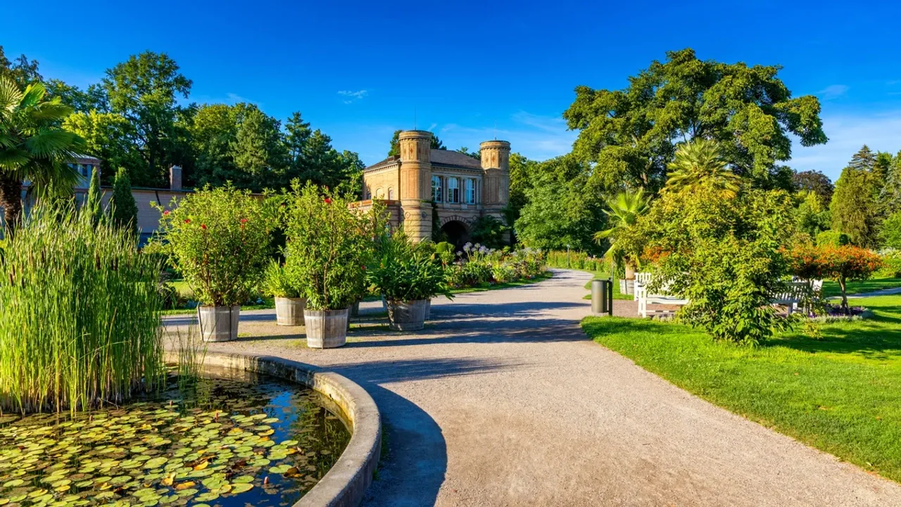 Ein Weg durch den Botanischen Garten, links der Teich, rechts das Gartenhaus