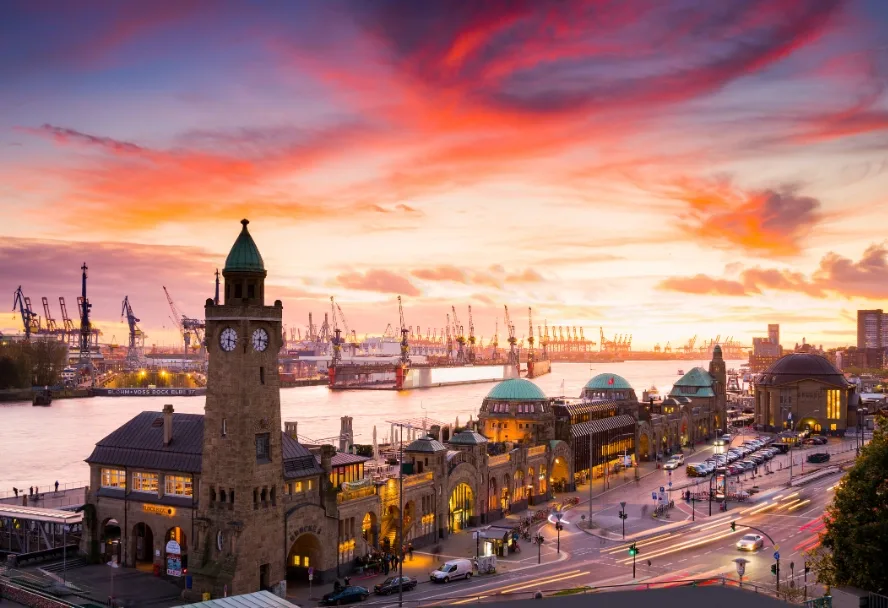 Die Landungsbrücken von oben bei rotem Abendhimmel, links der Pegelturm, dahinter die Hafenkräne