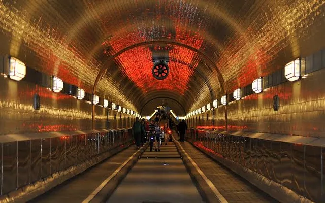 The tiled tube of the Alter Elbtunnel with its red-lit ceiling, pedestrians on their way through